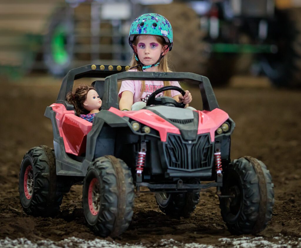 A girl in the back of an atv with doll.